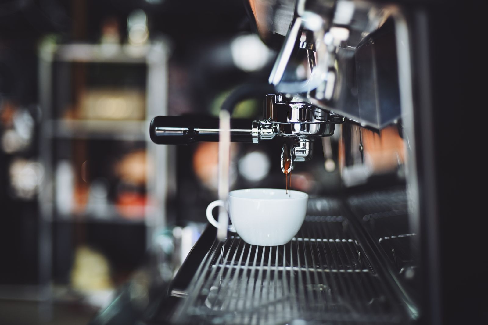 Close-up of espresso extracting into a cup under the group head