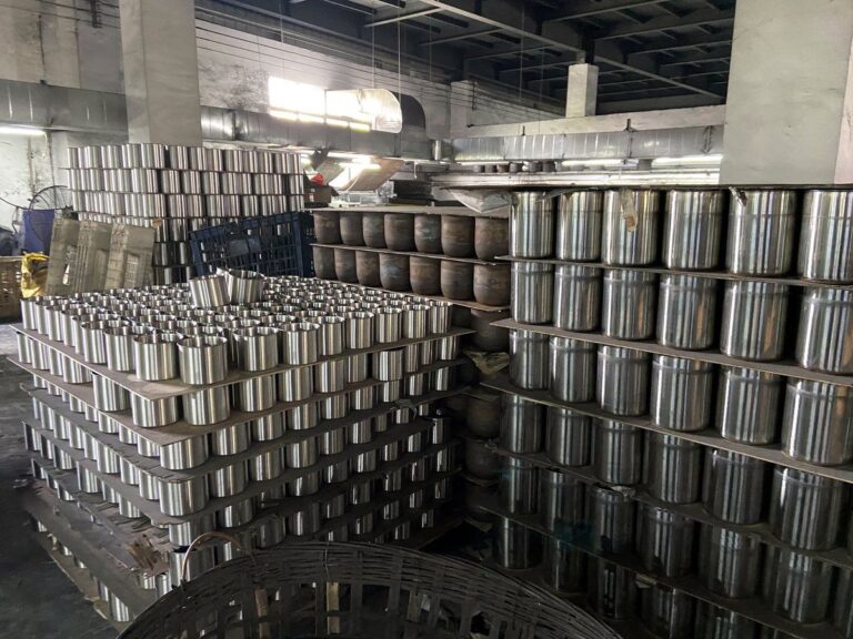 Stainless steel canister bodies stacked in the workshop awaiting finishing